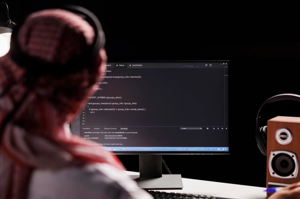 woman in headphones sitting in front of the computer screen with coding on it